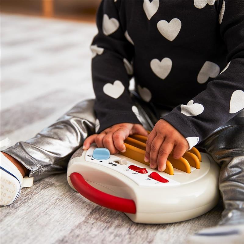 Toddler playing with Tiny Love Tiny Rockers Guitar, pressing colorful strings and buttons on a toy.