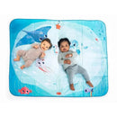Two babies lie on the Tiny Love Treasure The Ocean Outdoor Picnic Mat, featuring colorful ocean-themed designs.