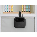 AI Smart Baby Monitor mounted on a light gray fabric storage bin, with colorful wooden beads in the background.