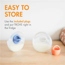 Silicone breast milk collection cups from Boon TROVE, featuring a blue plug and an orange plug, displayed on a wooden surface.