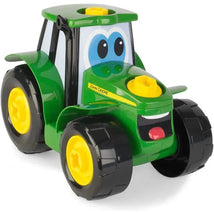 Green and yellow Tomy John Deere Build-A-Johnny tractor toy with a smiling face and large black wheels.