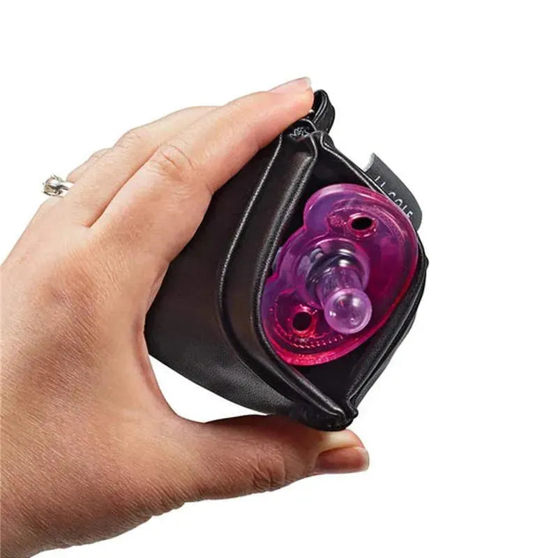 Hand holding a black pacifier pouch with a visible pink pacifier inside, designed for convenient storage.