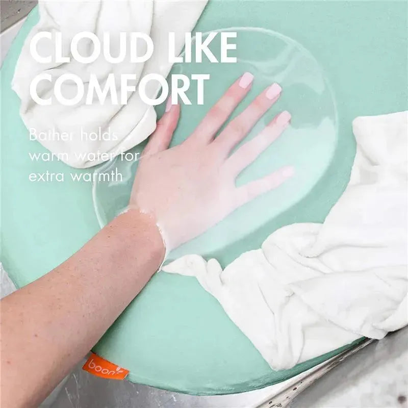 Puff Inflatable Bather in mint green, with a hand resting on it, showcasing comfort and warmth features.