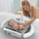 Tomy Rain Shower Spa Bath featuring a baby lying on a textured bathing mat, with a smiling caregiver interacting in a bathroom setting.