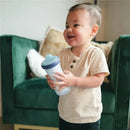 Toddler smiling while holding a Tomy - The First Years Bluey Insulated Sippy Cup in a cozy living room setting.