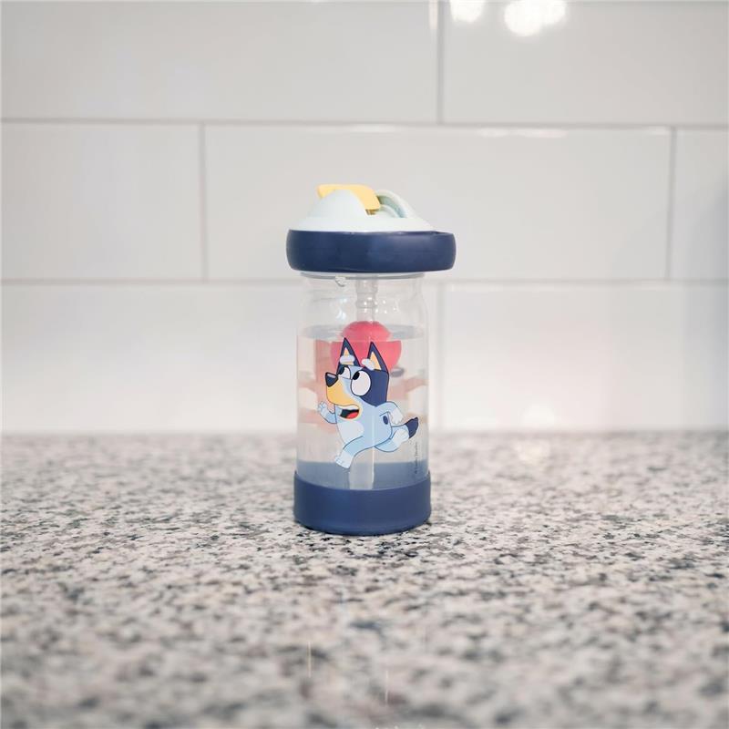 Toddler water bottle with a blue character design, featuring a straw and a floating charm, placed on a countertop.