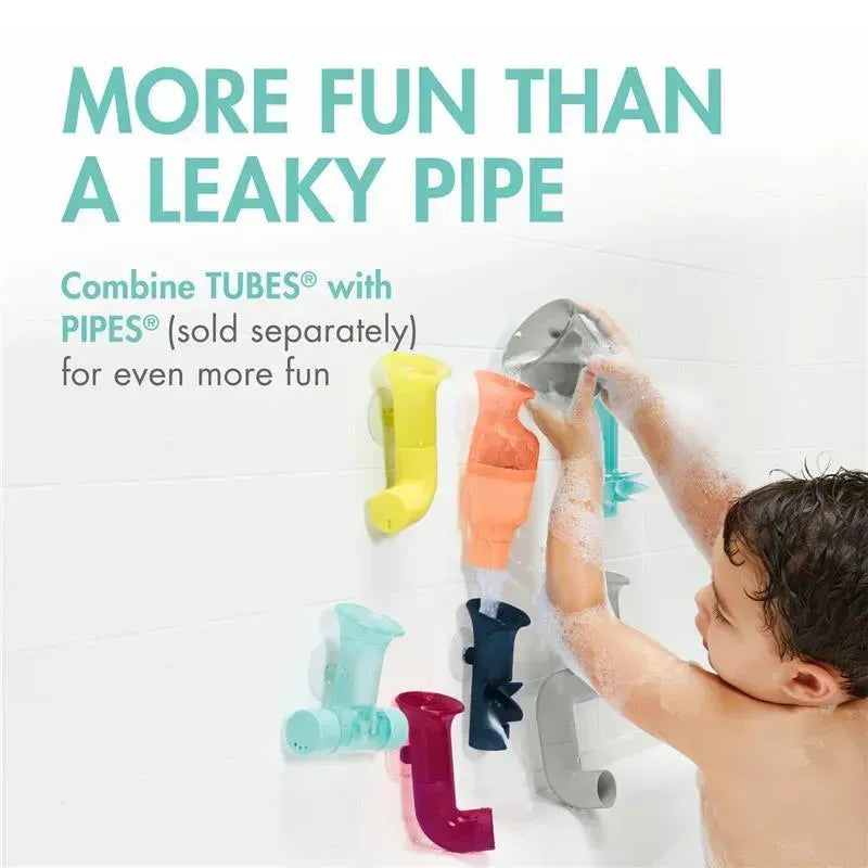 Colorful Tomy Tubes bath toys are attached to a wet wall, while a child pours water from a cup to create fun.