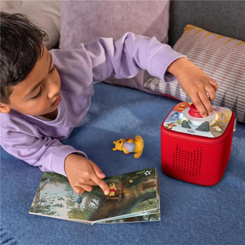 Child engaged with Tonieplay story game featuring a red Toniebox, pointing at a Winnie The Pooh book, with Tigger figure nearby.