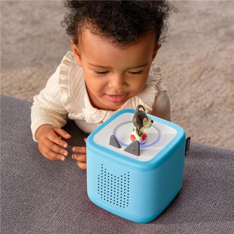 Child interacting with a blue Tonies Toniebox audio player featuring a playful puppy figure on top.