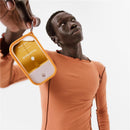 Frosty blue silicone case with keyring for Touchland hand sanitizer mist, held by a person in an orange shirt.