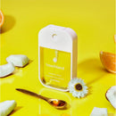 Touchland Vanilla Blossom Power Mist Hydrating Hand Sanitizer in a yellow background with coconut, orange slices, and a golden spoon.