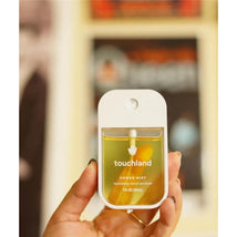 Touchland Vanilla Blossom Power Mist Hydrating Hand Sanitizer in a clear bottle held in a hand, featuring a white cap and applicator.