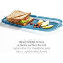 Reusable silicone storage bag in juniper, containing a sandwich, apple slices, and almonds, promoting clean eating surfaces.