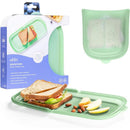 Reusable silicone storage bag by Ubbi, shown with a sandwich and snacks on a green placemat.