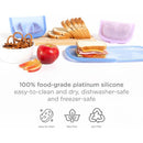 Reusable silicone storage bags in Smoothie Purple, ideal for food storage, alongside an apple, pretzels, and sandwich.