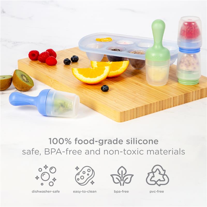 Ubbi Baby Food Feeder & Freezer Tray Set in Polaris Blue and Zest Green with fruits on a wooden cutting board.