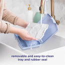 Hands washing the Ubbi Bento Lunch Box in sage green under running water, highlighting its removable tray and rubber seal.