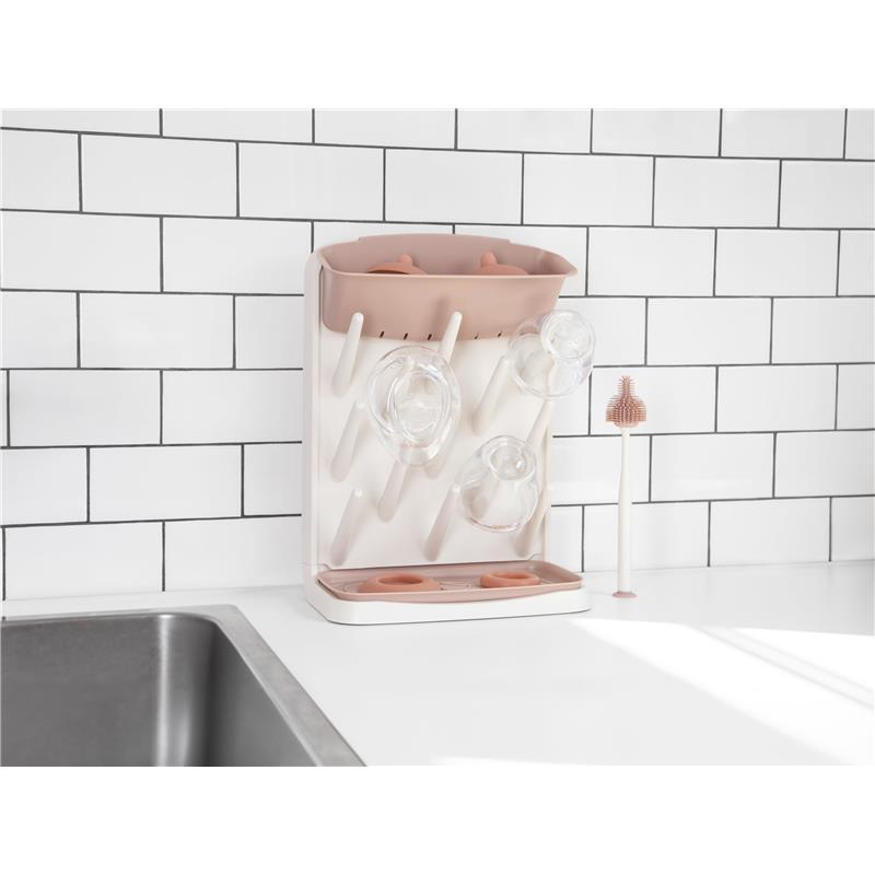 Vertical drying rack with clear bottles and an upper holder, set against a white tiled background.