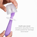 A hand holds a purple toothbrush with a textured head, featuring a clear cover that secures to a choke guard for travel.