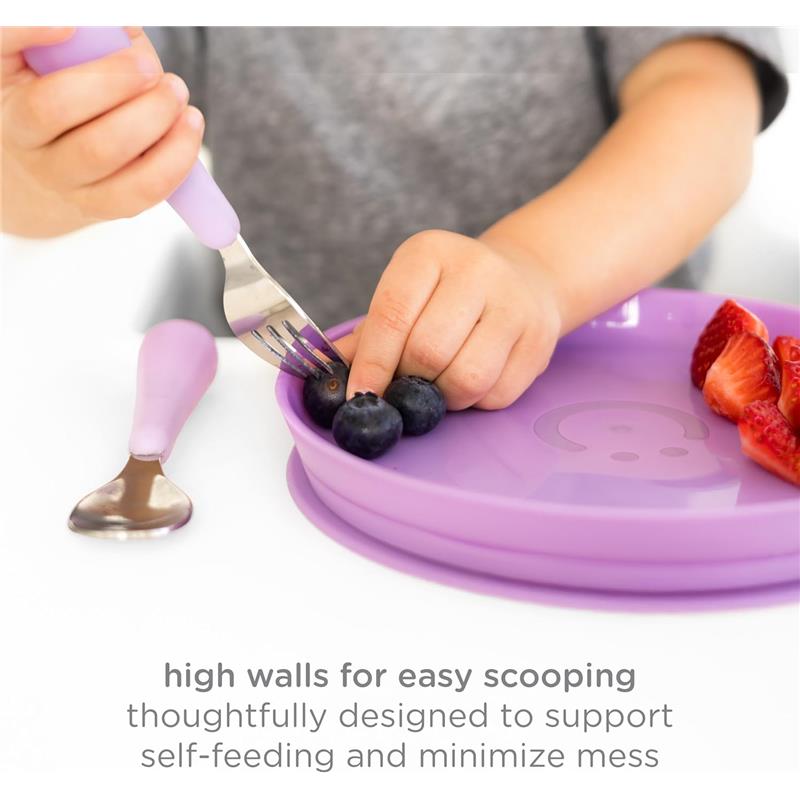 Plate set for babies showing a child using a fork to scoop blueberries from a purple plate with high walls, promoting self-feeding.
