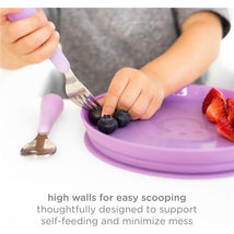 Plate set for babies showing a child using a fork to scoop blueberries from a purple plate with high walls, promoting self-feeding.