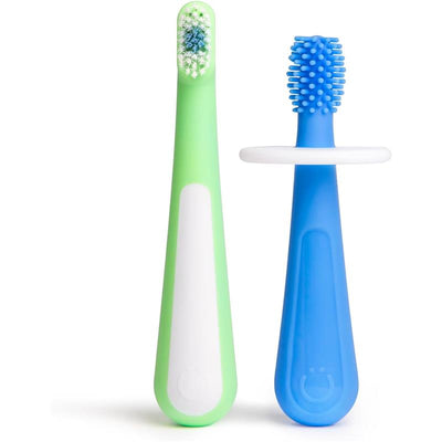 Two toddler toothbrushes in green and blue. The green brush has soft bristles, and the blue brush features a textured head.