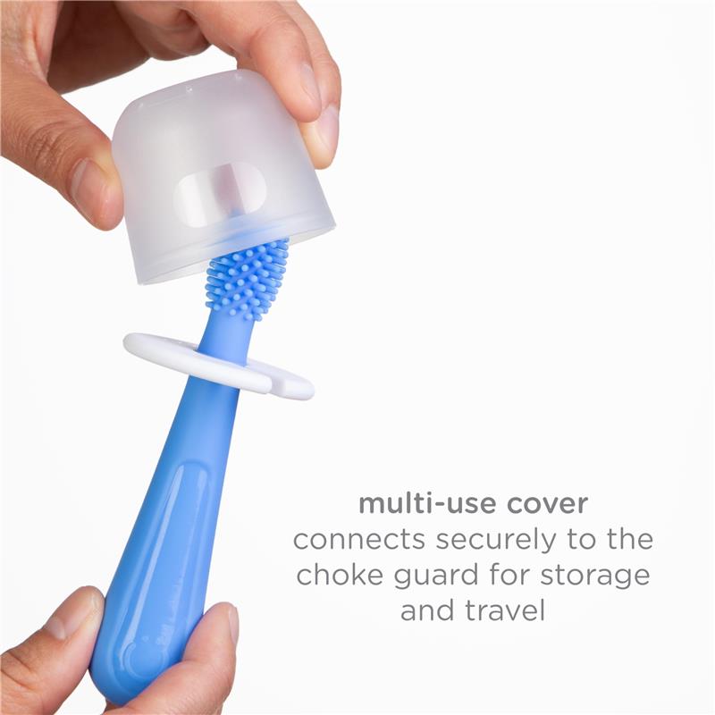 A hand holds a blue toddler toothbrush with a soft bristle head covered by a transparent cap; a choke guard is visible.