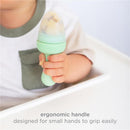 Blue Ubbi baby food feeder with an ergonomic handle, held by a child, designed for easy gripping.