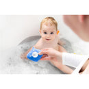 Blue floating silicone baby bath thermometer shaped like a stingray shows temperature reading; a smiling infant is in the bath.
