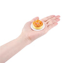 Miniature dessert, resembling a cupcake with caramel topping and sprinkles, placed on a hand.