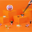 Mini Brands Master Chef Series 2 features miniature food replicas on vibrant orange display blocks, including sushi, tacos, and desserts.