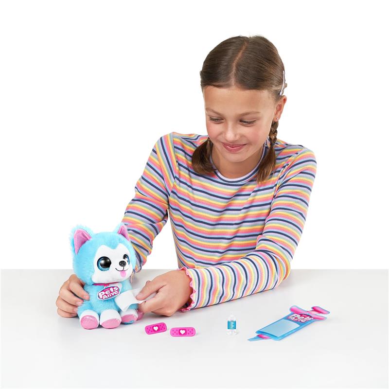 Girl in a striped long-sleeve shirt cares for a blue plush puppy from the Pets Alive series, with accessories nearby.