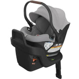 Uppababy Aria Infant Car Seat in Light Grey, featuring adjustable handle, protective canopy, and safety labels on the base.