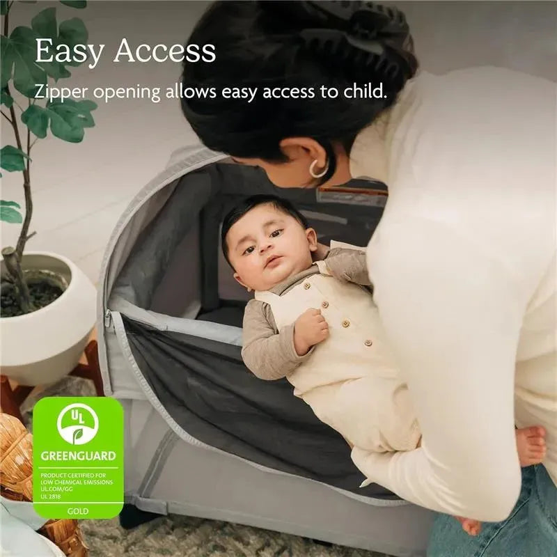 Zippered canopy allows easy access to a child in the Uppababy Remi Playard, featuring a parent lifting the baby.