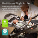 Uppababy Cruz V3 Stroller in Dusty Blue Mélange with a chestnut leather handle, featuring a newborn securely strapped inside, while a caregiver interacts.