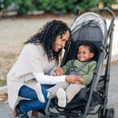 A smiling mother interacts with her happy toddler in a UPPAbaby G-Series stroller, showcasing its comfortable design.