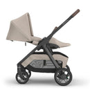 Uppababy Kona Stroller in Ada (Sandstone Mélange) with a beige seat and canopy, featuring a sleek black frame and wheels.