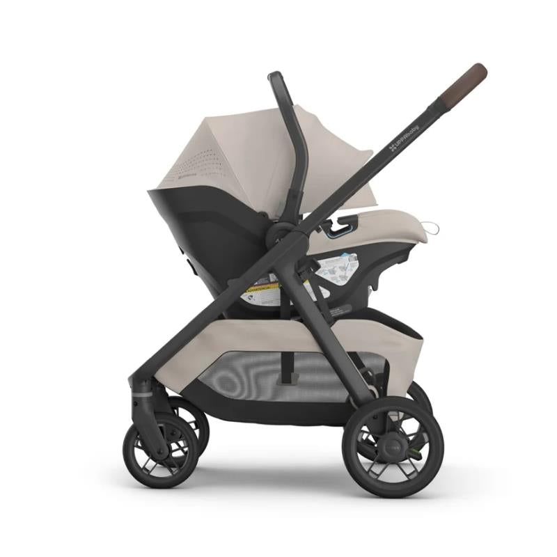 Uppababy Kona stroller and bassinet V3 bundle in Sandstone Mélange, featuring a sleek design with a dark frame and light beige fabric.