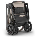 Uppababy Kona Stroller in Ada color, featuring a sleek design with a beige seat and a compact fold for easy transport.