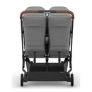 Compact double stroller with charcoal mélange fabric and carbon frame, featuring saddle leather handlebars.