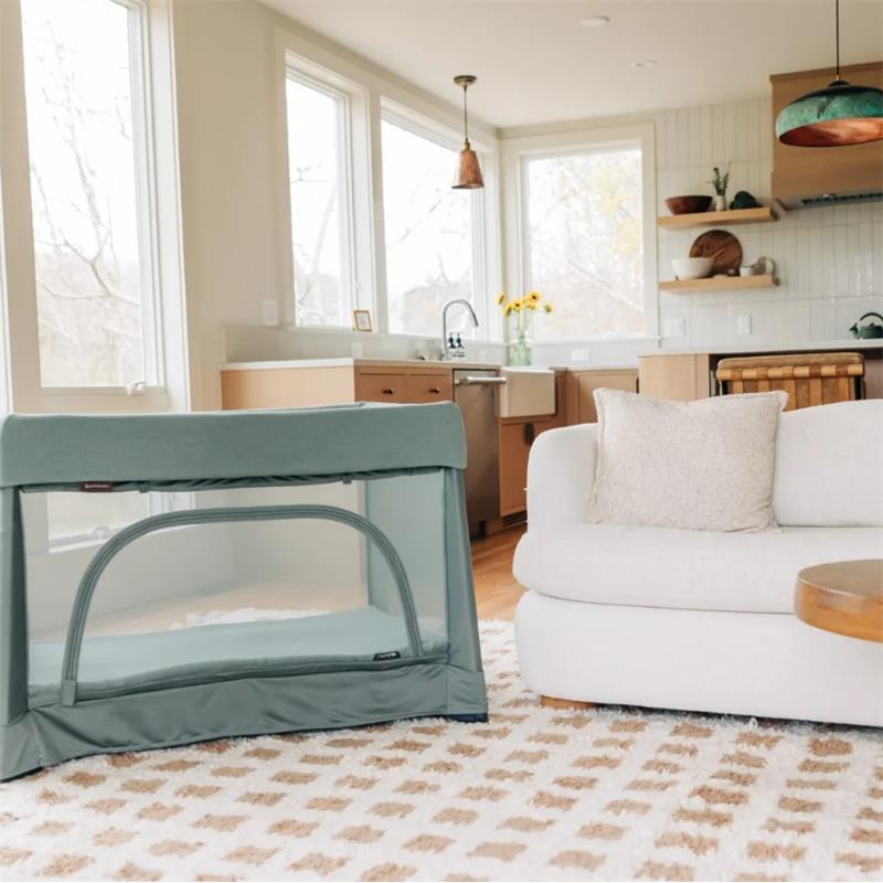 UPPAbaby Remi V2 Playard in Maddie Green Soft Knit set up in a living room, showcasing a modern, inviting space with sunlight.