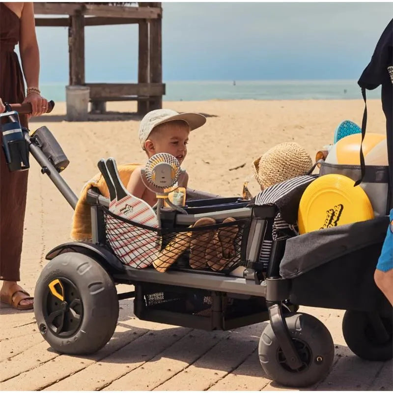 Cargo net storage attachment for the Veer wagon, filled with beach gear and a child, set on a sandy beach.
