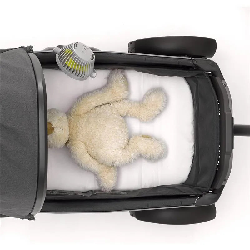 Portable baby stroller fan attached to a stroller, with a plush teddy bear lying on a white bedding inside.