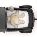 Portable baby stroller fan attached to a stroller, with a plush teddy bear lying on a white bedding inside.