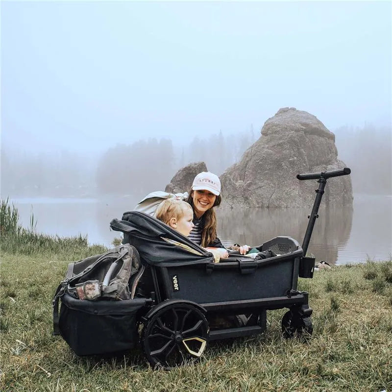 Rear foldable storage basket for Veer All-Terrain Cruiser, featuring a child and a smiling woman near a lake.