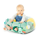 Baby seated in a colorful Vulli Sophie La Girafe play seat with interactive toys and a smiling expression.