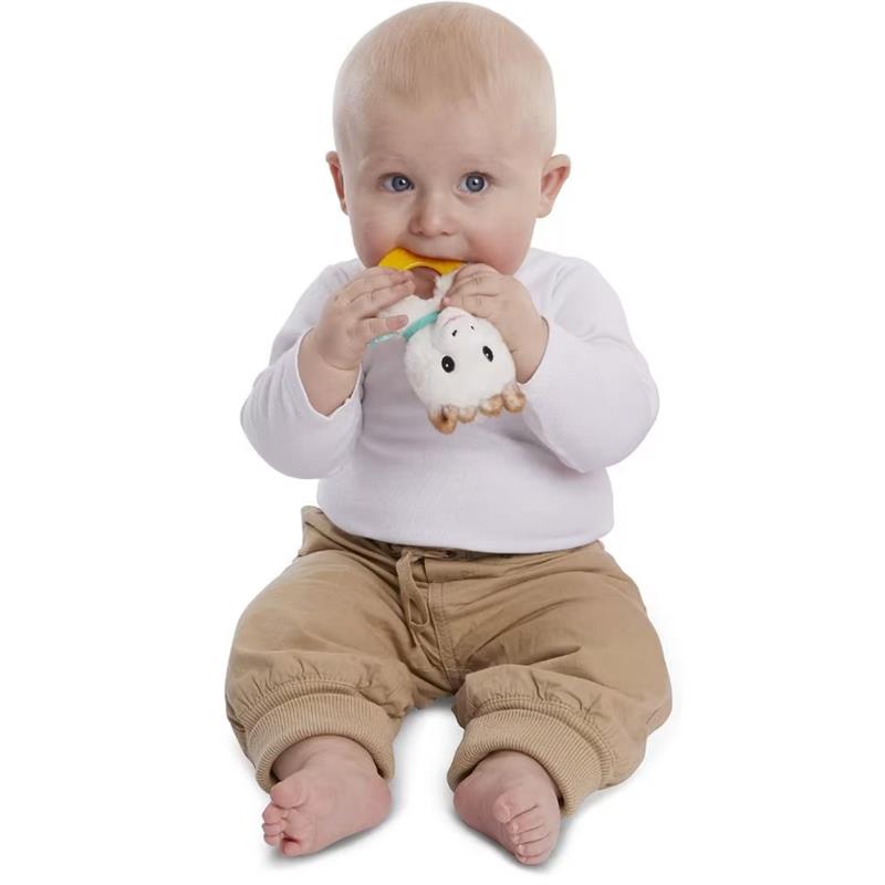 Baby sitting on the floor, grasping a Vulli Sophie La Girafe Sweetie Plush Rattle with a yellow teething toy attached.