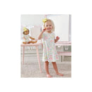 Baby girl in a floral dress smiles while holding a crayon, with a doll in a matching outfit beside her.