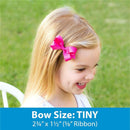 Classic grosgrain hair bow with scalloped edges in bright pink on a girl’s hair, showing size details below.
