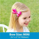 Mini pink satin hair bow on a WeeStay clip worn by a smiling girl with blonde hair, outdoor background.